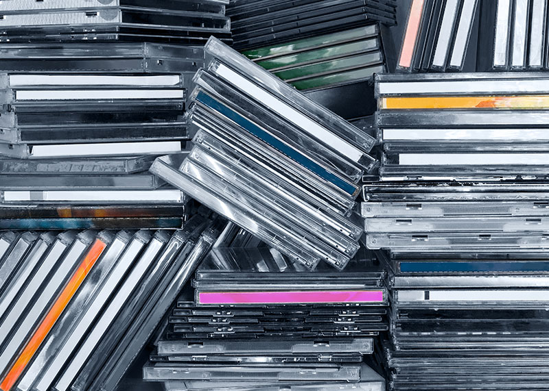 Cajas de CDs apiladas en un estante sin un orden aparente.