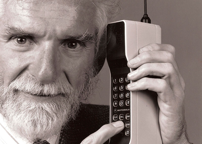 Martin Cooper sosteniendo un teléfono móvil Motorola de los años 70s.