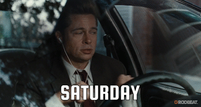 man wearing a gray suit dances in his car, caption says “SATURDAY”